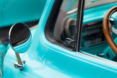 Close-up of wing mirror of a blue shiny classic vintage car