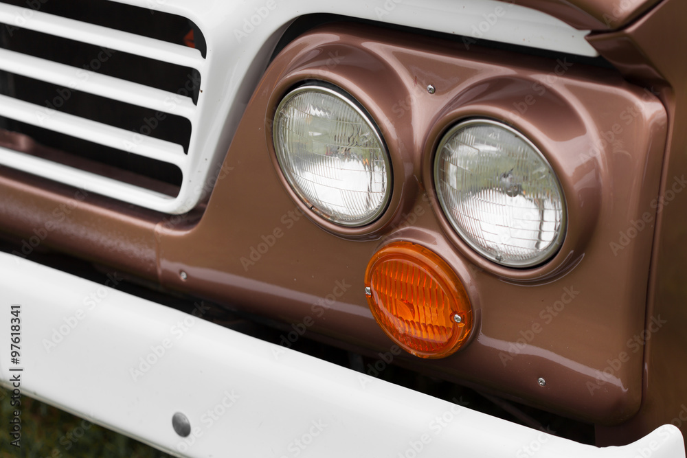 Close-up of right headlights of a brown shiny classic vintage car
