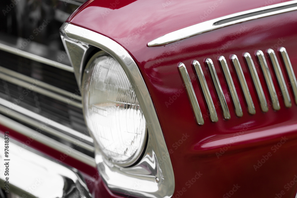 Close-up of right headlight of a maroon shiny classic vintage car
