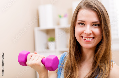 Happy young woman working out with dumbbells
