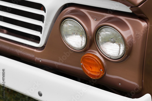 Close-up of right headlights of a brown shiny classic vintage car