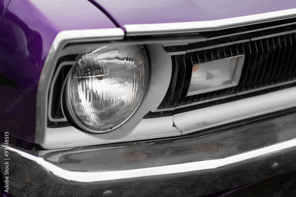 Close-up of left headlight of a purple shiny classic vintage car