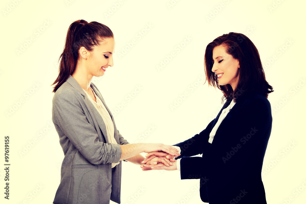 Two businesswomen holding their hands together. Two businesswomen holding their hands together.