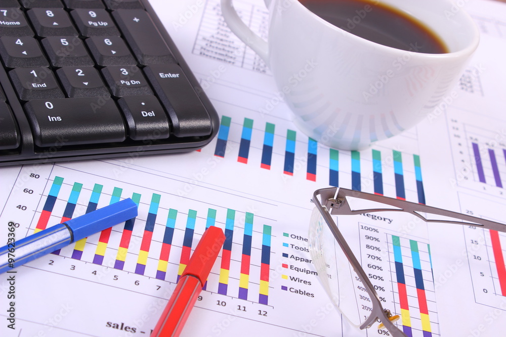 Pen, glasses, computer keyboard and cup of coffee on financial graph, business concept Pen, glasses, computer keyboard and cup of coffee on financial graph, business concept