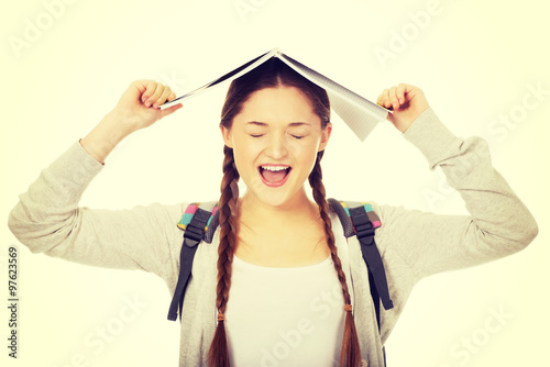Teen girl with book over her head.