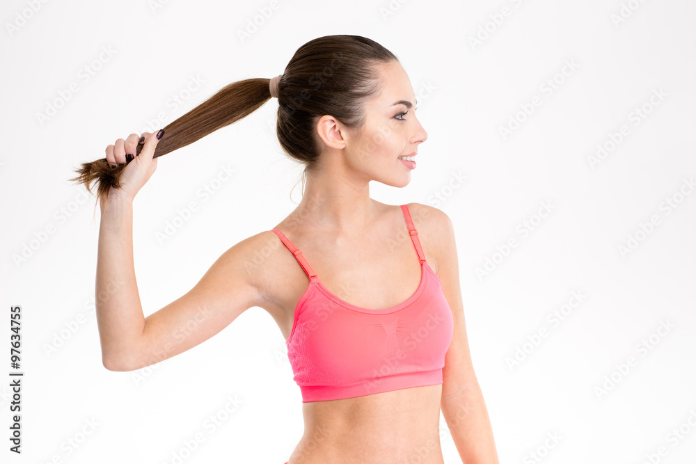 Profile of sportswoman in pink top holding up her ponytail