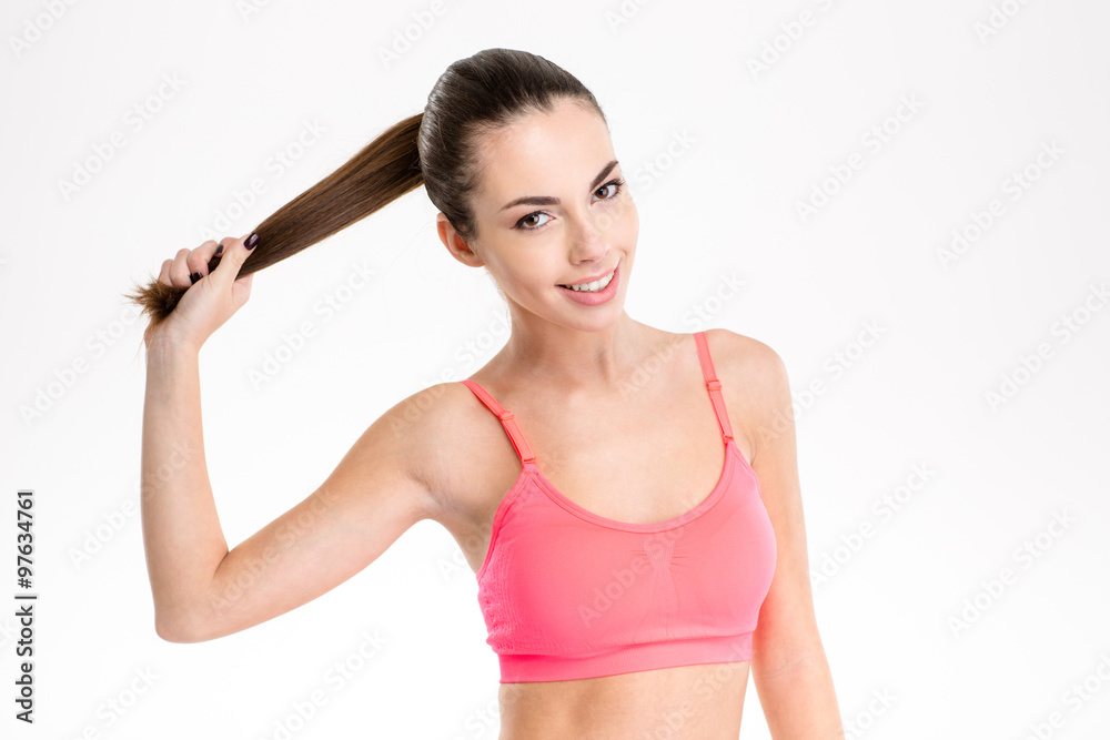 Amusing cheerful fitness girl holding her long hair in ponytail Amusing cheerful fitness girl holding her long hair in ponytail