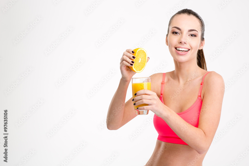 Fitness girl pressing orange juice into a glass Fitness girl pressing orange juice into a glass