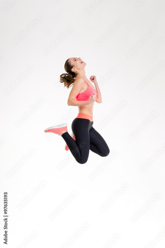 Attractive excited fitness girl in sportwear jumping of joy