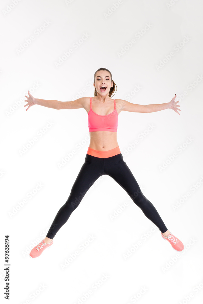 Beautiful cheerful young sportswoman jumping in the air