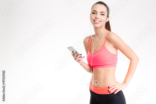 Fitness girl listening to music from cell phone using earphones