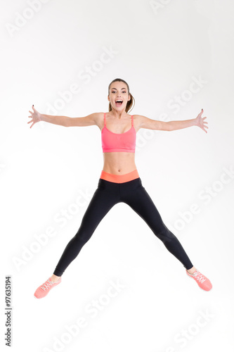 Beautiful cheerful young sportswoman jumping in the air