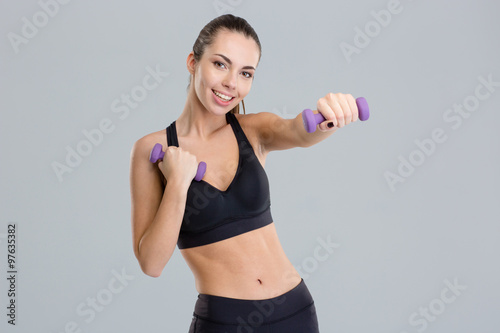 Positive pretty fitness girl exercising with dumbbells