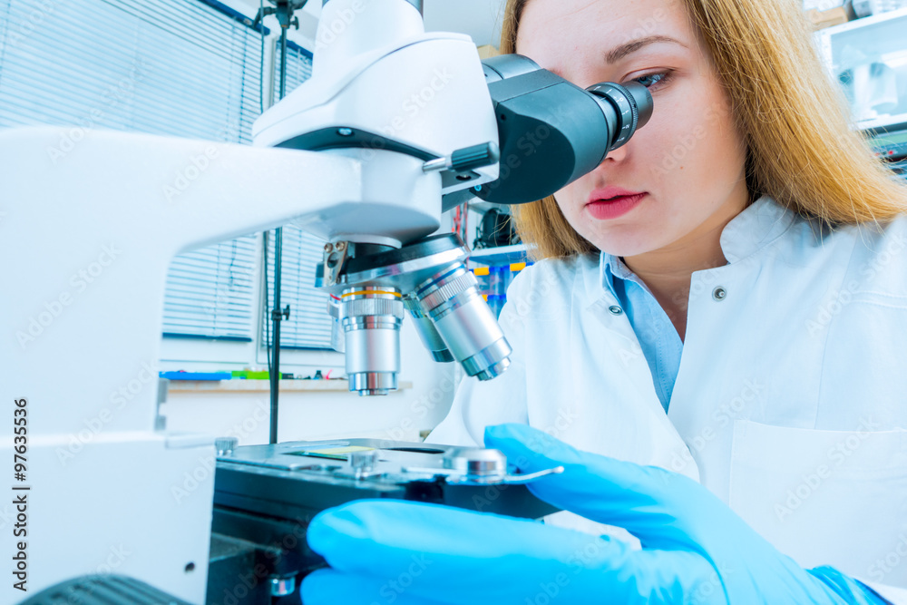 Scientist using a microscope in a laboratory Scientist using a microscope in a laboratory