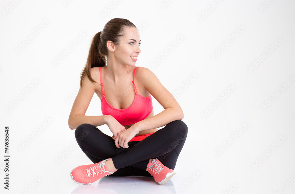 Happy fitness woman sitting with folded legs and looking away