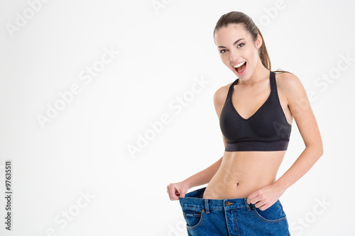 Fitness woman showing that jeans became too big for her
