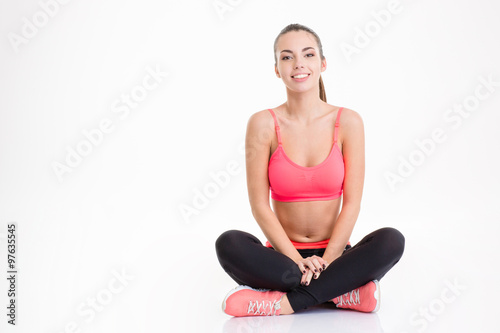 Fototapeta Naklejka Na Ścianę i Meble -  Cheerful attractive young sportswoman sitting with legs crossed