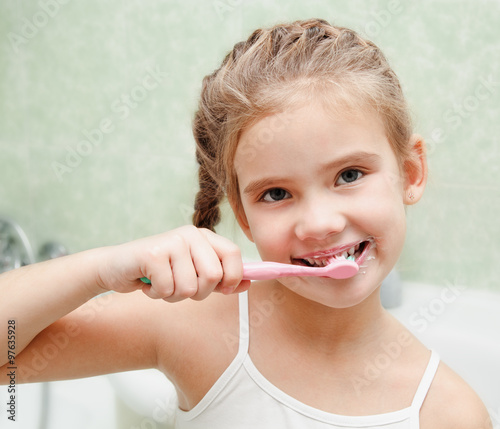 Smiling cute little girl brushing teeth