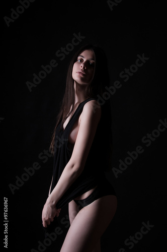 Sexy brunette tan girl with long hair over dark background, studio shot