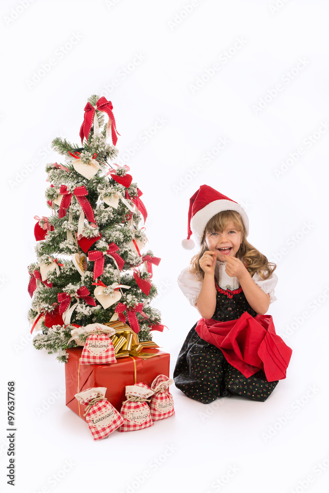 Bambina sorridente con abito tradizionale e albero di Natale con regali