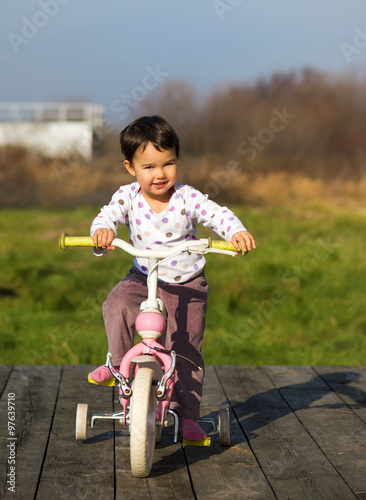 Fototapeta Naklejka Na Ścianę i Meble -  little girl on a bike near the house