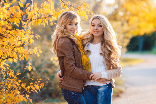 Two beautiful blonde in autumn park.