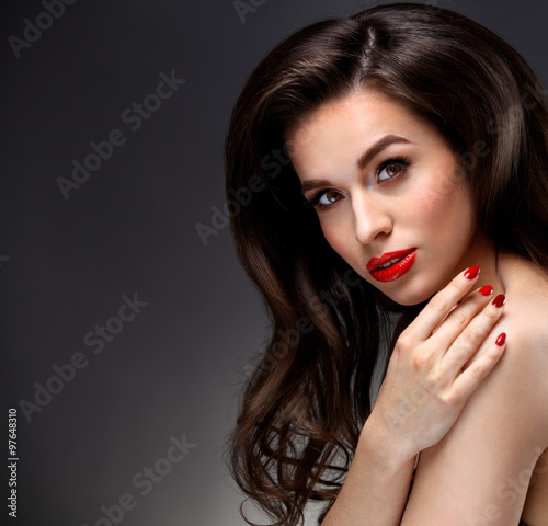 Beauty Model Woman with Long Brown Wavy Hair. Healthy Hair and Beautiful Professional Makeup. Red Lips and Smoky Eyes Make up. Gorgeous Glamour Lady Portrait. Haircare, Skincare concept