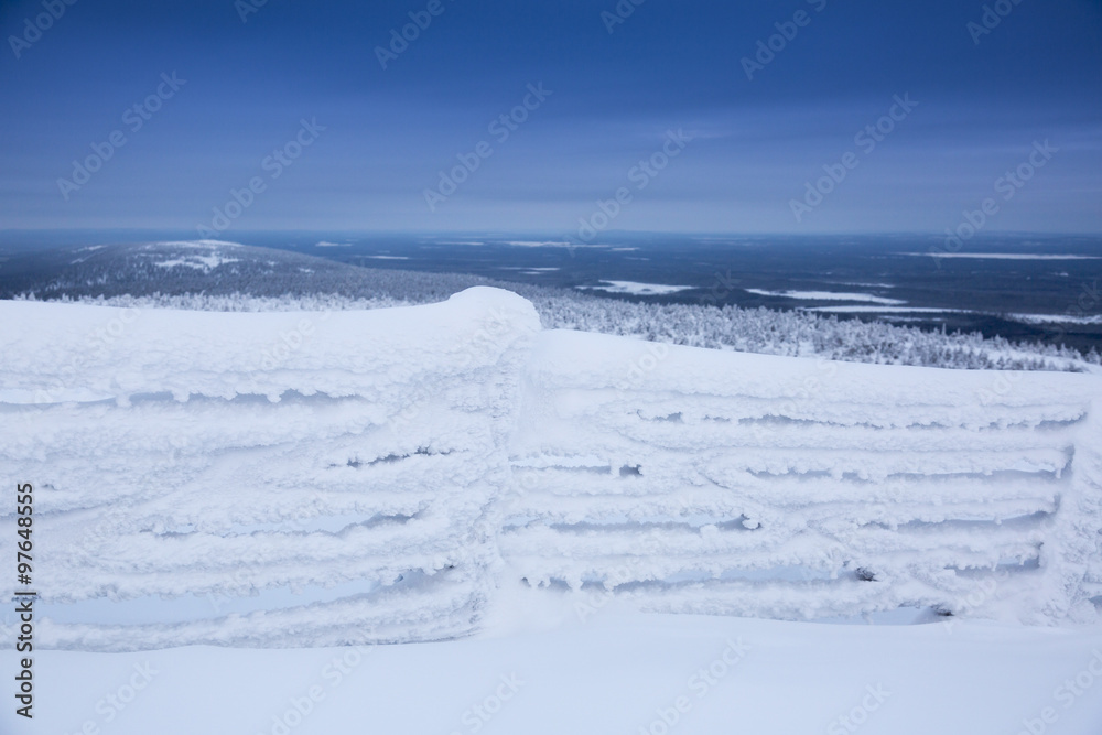 frozen fence covered with snow against mountains background