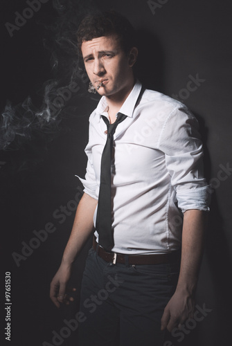 Slika na platnu Young smoker with rolled up sleeves looking at camera