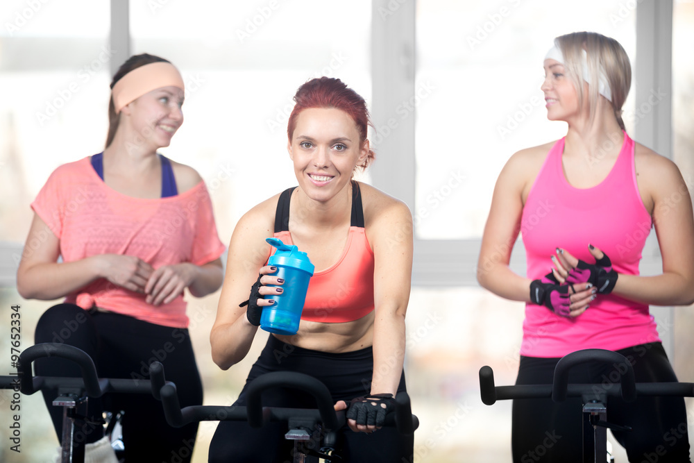 Three women relaxing after cardio exercises on cycles Three women relaxing after cardio exercises on cycles