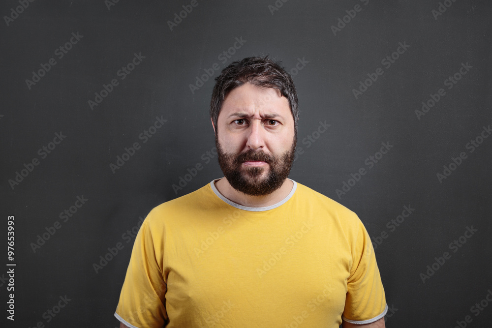 Frowning man looking at the camera. On dark chalkboard Frowning man looking at the camera. On dark chalkboard