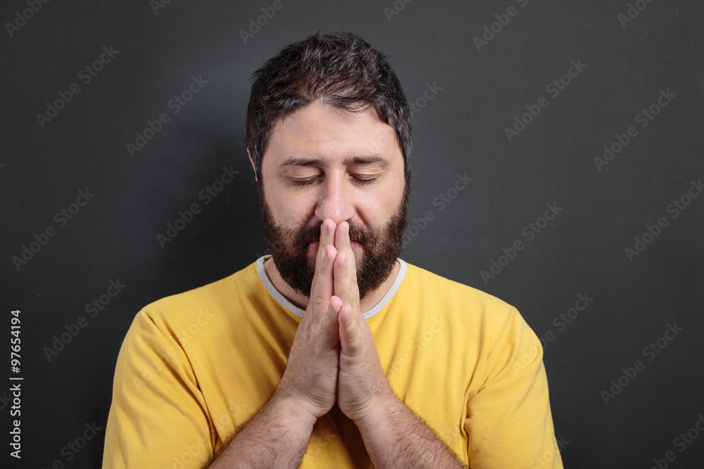 Praying man in front of dark chalkboard Praying man in front of dark chalkboard