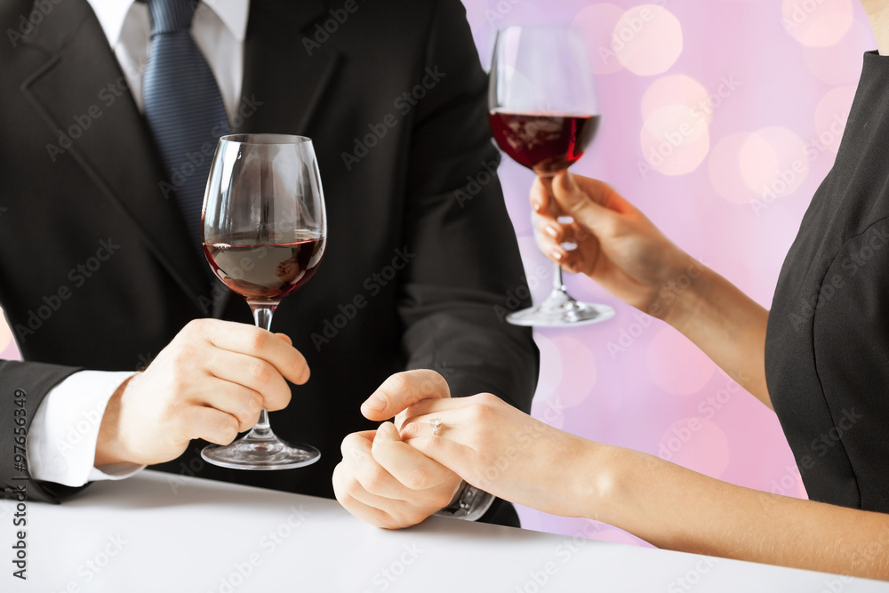 hands of couple with diamond ring and wine glasses hands of couple with diamond ring and wine glasses