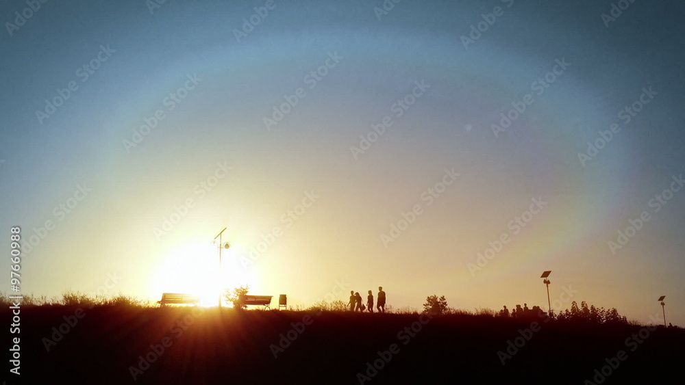 People silhouettes in park, sun shining behind People silhouettes in park, sun shining behind