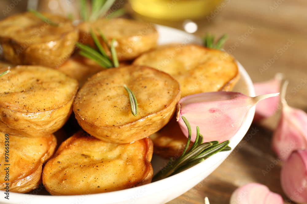 Delicious baked potato with rosemary in bowl on table close up Delicious baked potato with rosemary in bowl on table close up