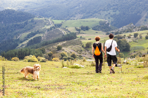 man and woman and dog on a summer walk in the mountains of Europe