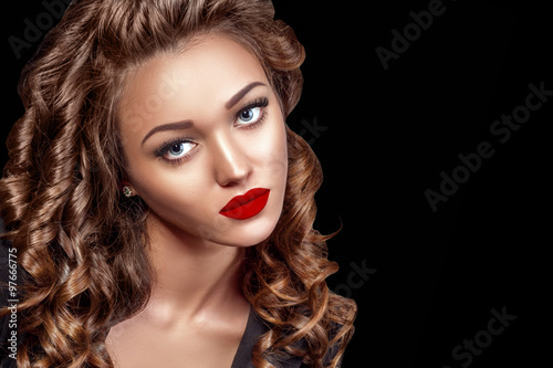 Beautiful Woman Model with Curls, Red Matte lips. Beauty face closeup. Isolated on Black Background. Long Shiny Curly Hair. Hairstyle..