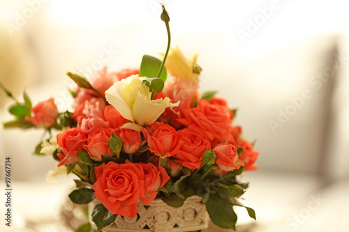 Beautiful rose in vase on table in room on bright background