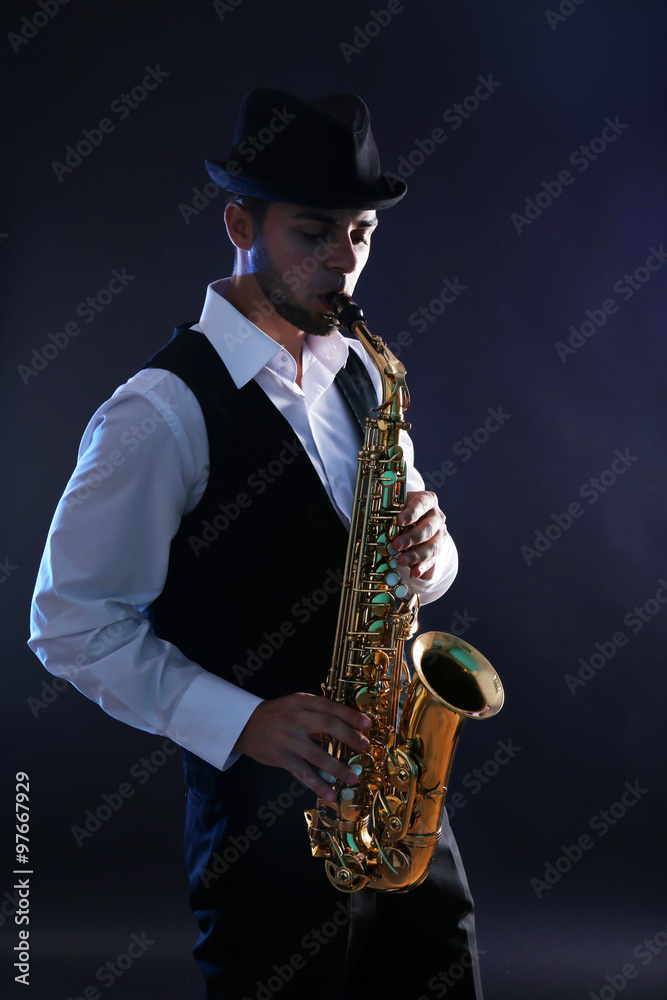 Naklejka premium Elegant saxophonist plays jazz on dark background