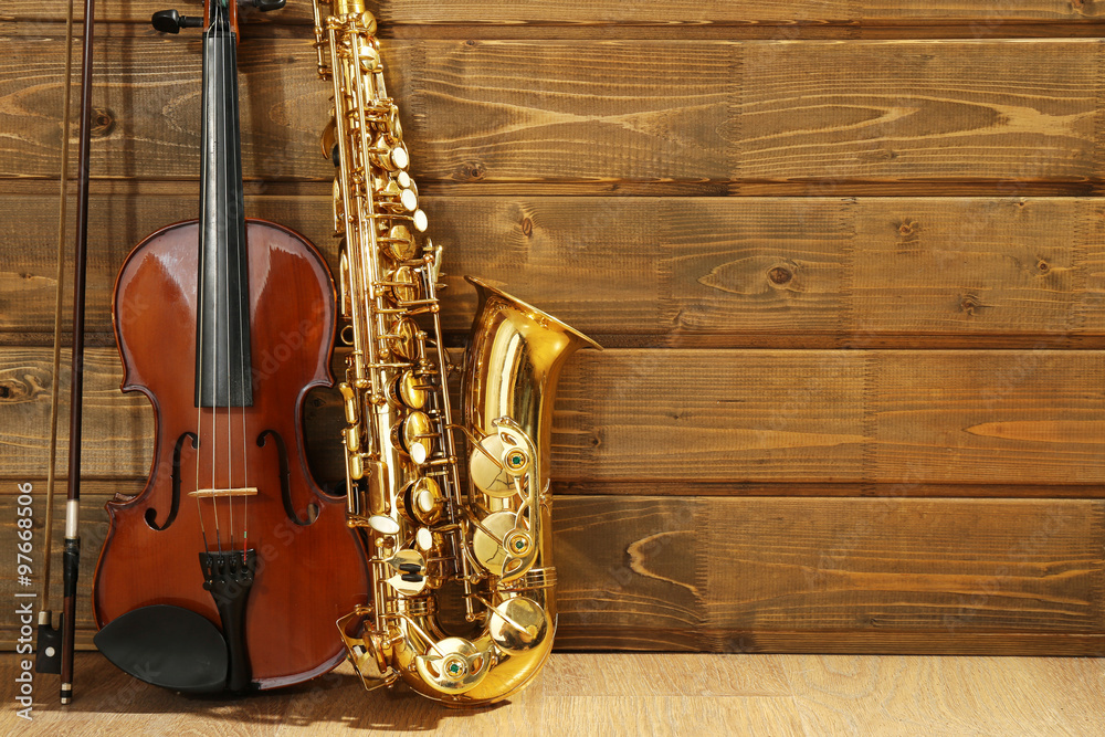 Naklejka premium Violin and saxophone on wooden background