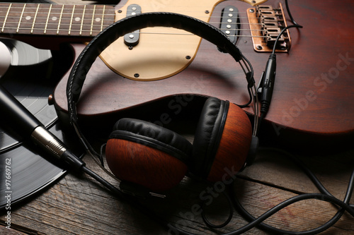 Electric guitar and headphones with vinyl on wooden background
