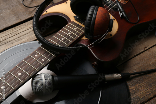 Electric guitar and headphones with microphone and vinyl on wooden background