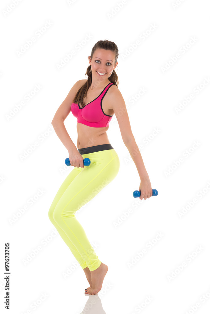 Pretty sportive smiling brunette woman in sports neon yellow leggings and pink bra doing complex exercises for muscles of back, legs, buttocks and hands using blue dumbbells on white background. Pretty sportive smiling brunette woman in sports neon yellow leggings and pink bra doing complex exercises for muscles of back, legs, buttocks and hands using blue dumbbells on white background.