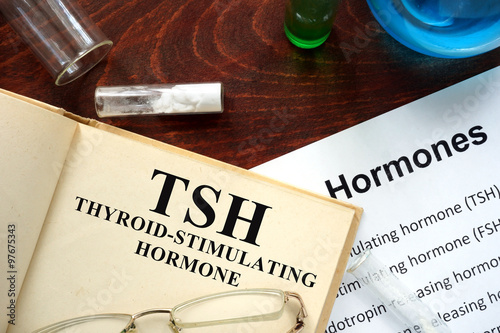 Thyroid-stimulating hormone (TSH) written on book. Test tubes and hormones list. photo