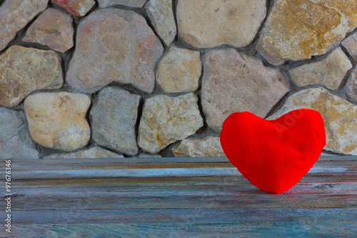 plush red heart on the background of a stone wall, the concept of love and romance. Free space for text. Copy space