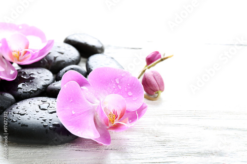 Beautiful composition of orchid and pebbles on white wooden background, close up