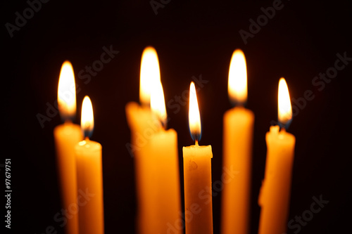 Many burning candles on black