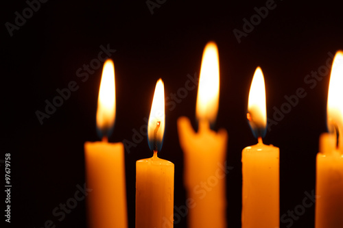 Many burning candles on black