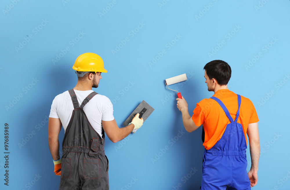 Two workers renewing apartment on wall background Two workers renewing apartment on wall background