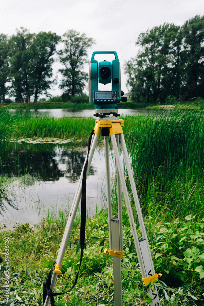 blue surveying equipment total station on a background of lake and forest blue surveying equipment total station on a background of lake and forest